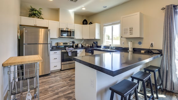 A modern kitchen with white cabinets, stainless steel appliances, and a large island with bar stools.
