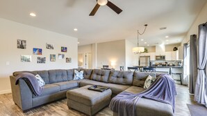 A modern living room with a sectional sofa, ottoman, and artwork on the walls.