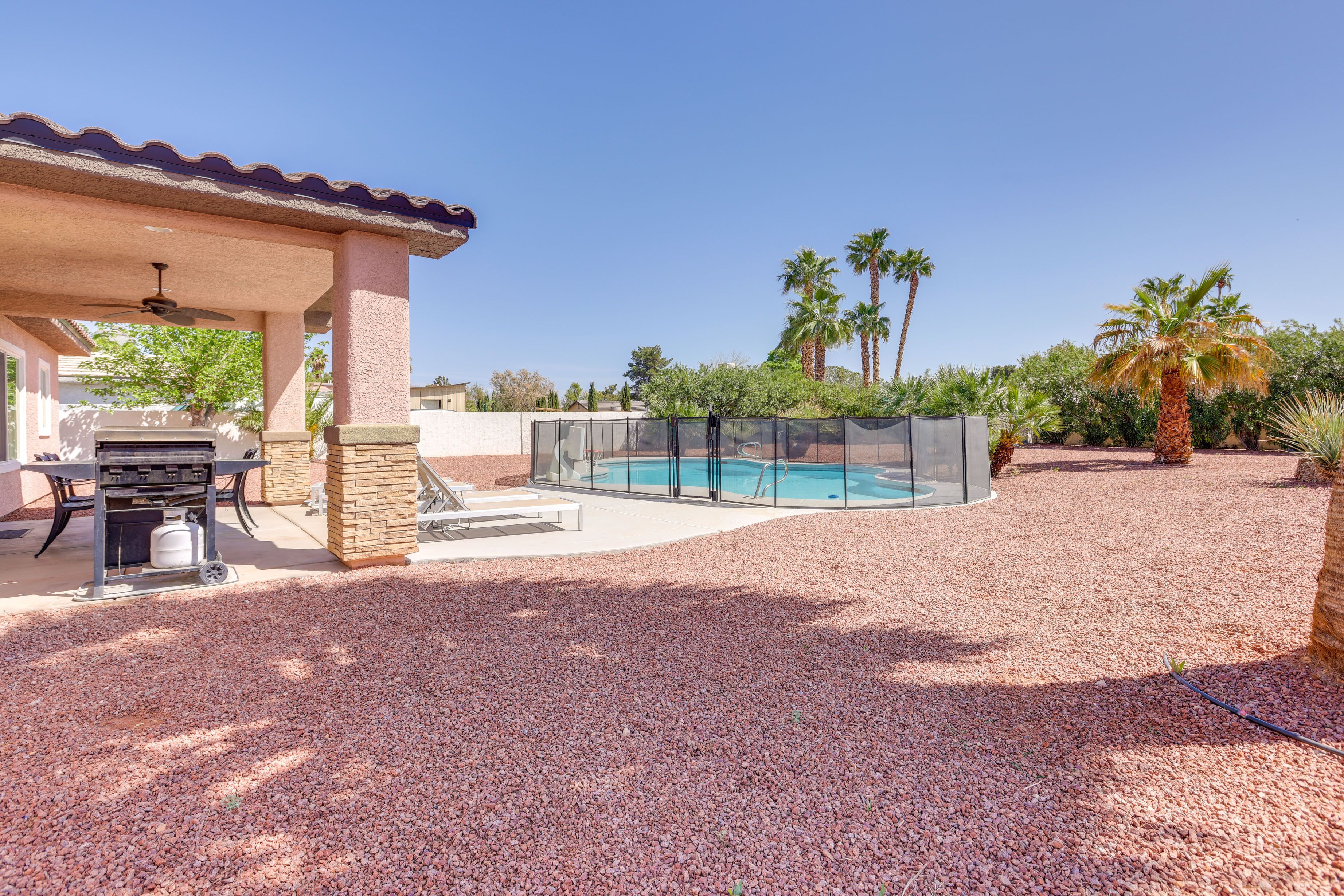 A backyard with a pool, patio furniture, and a covered seating area.