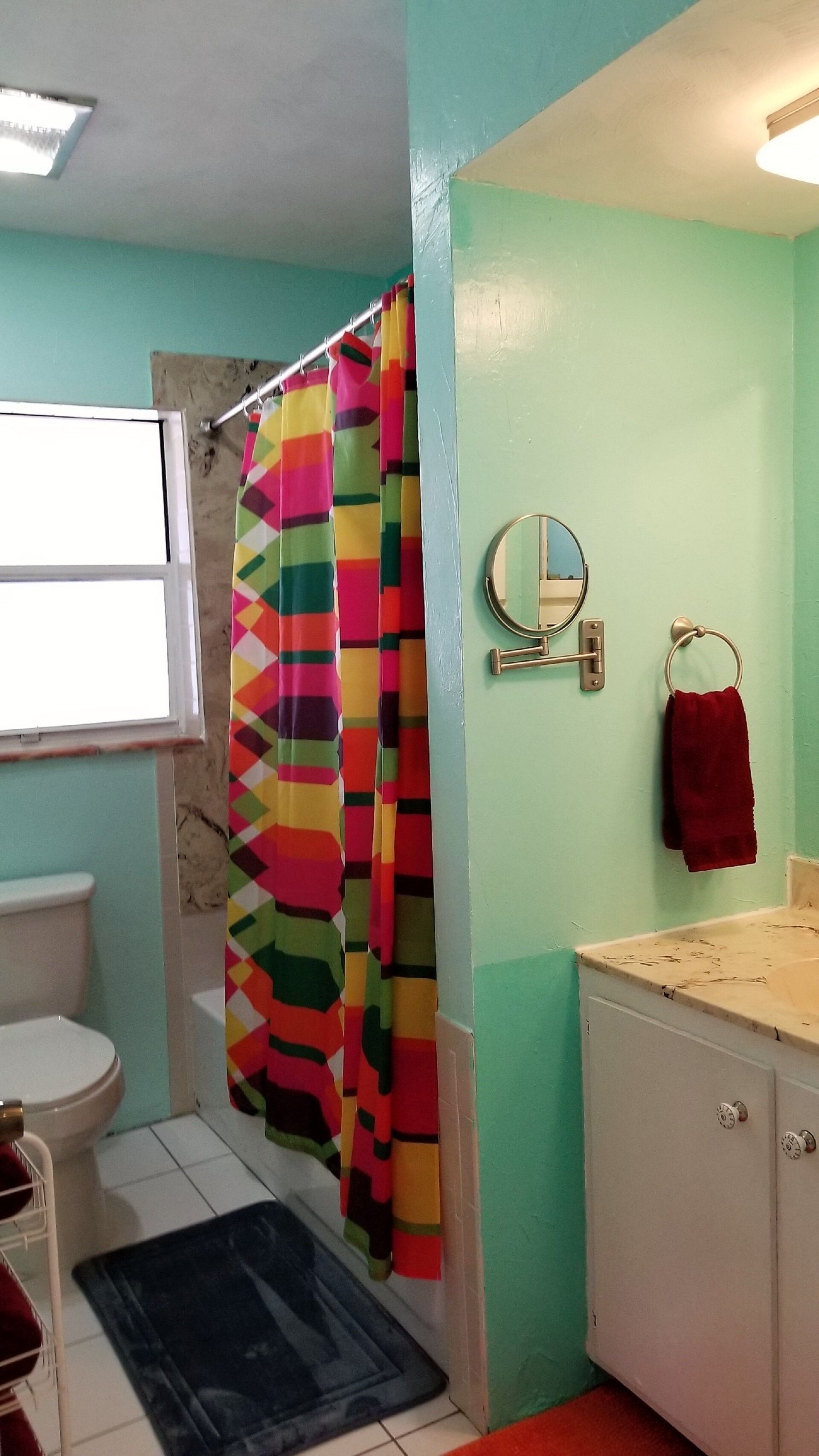 A bathroom with a shower curtain, a mirror, a towel rack, a toilet, and a sink.