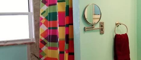A bathroom with a shower curtain, a mirror, a towel rack, a toilet, and a sink.