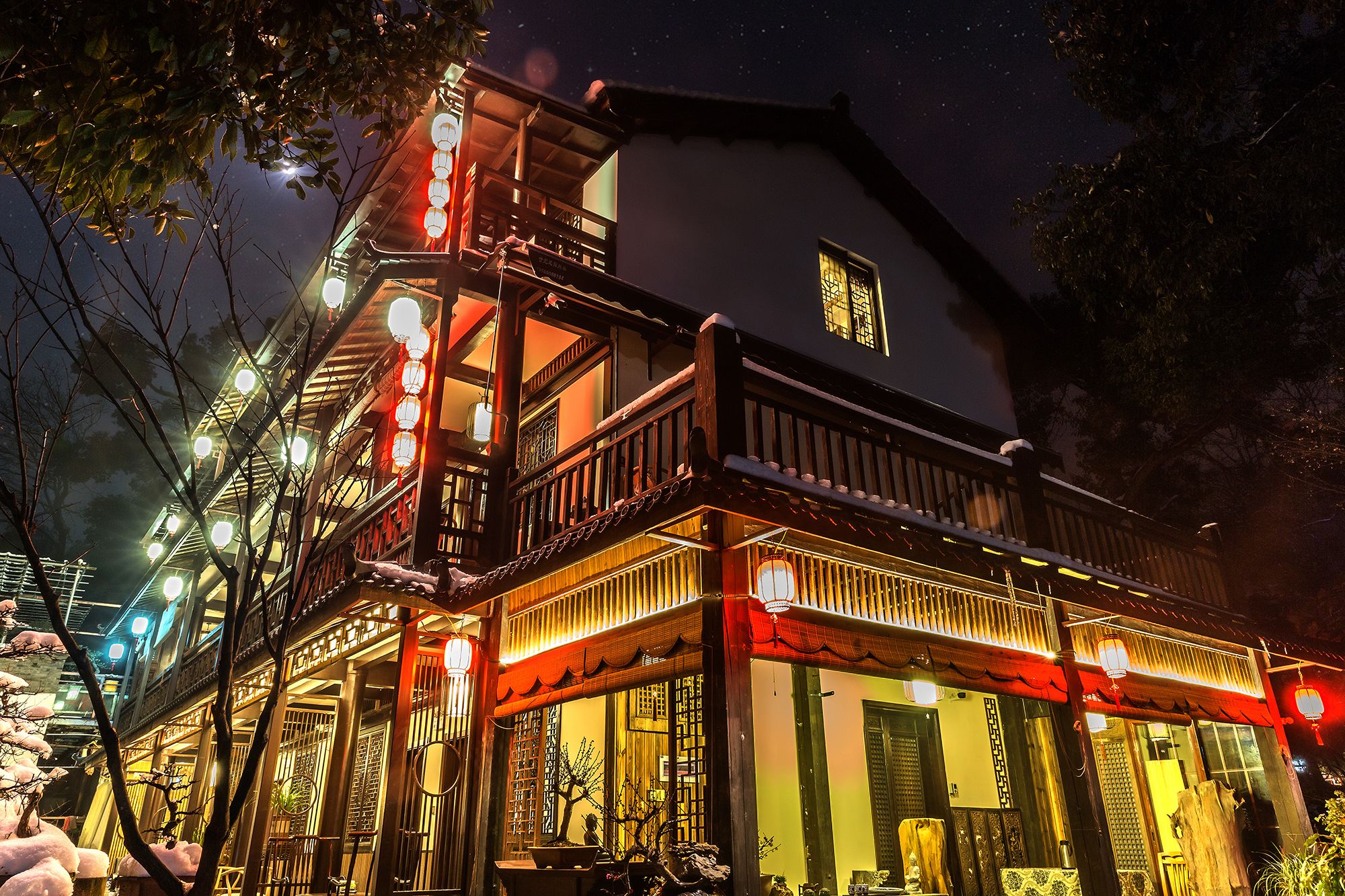 Un edificio tradicional de varios niveles, con balcones de madera y ventanas iluminadas.
