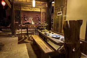 A traditional wooden interior with a stone bench, a table with tea set, and a bonsai tree. - FTYS Hostel (Hangzhou)