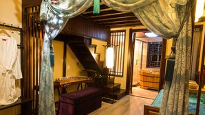 Une pi èce à l’ambiance traditionnelle, avec un plancher en bois, un banc violet, un instrument de musique à cordes et une baignoire en bois.