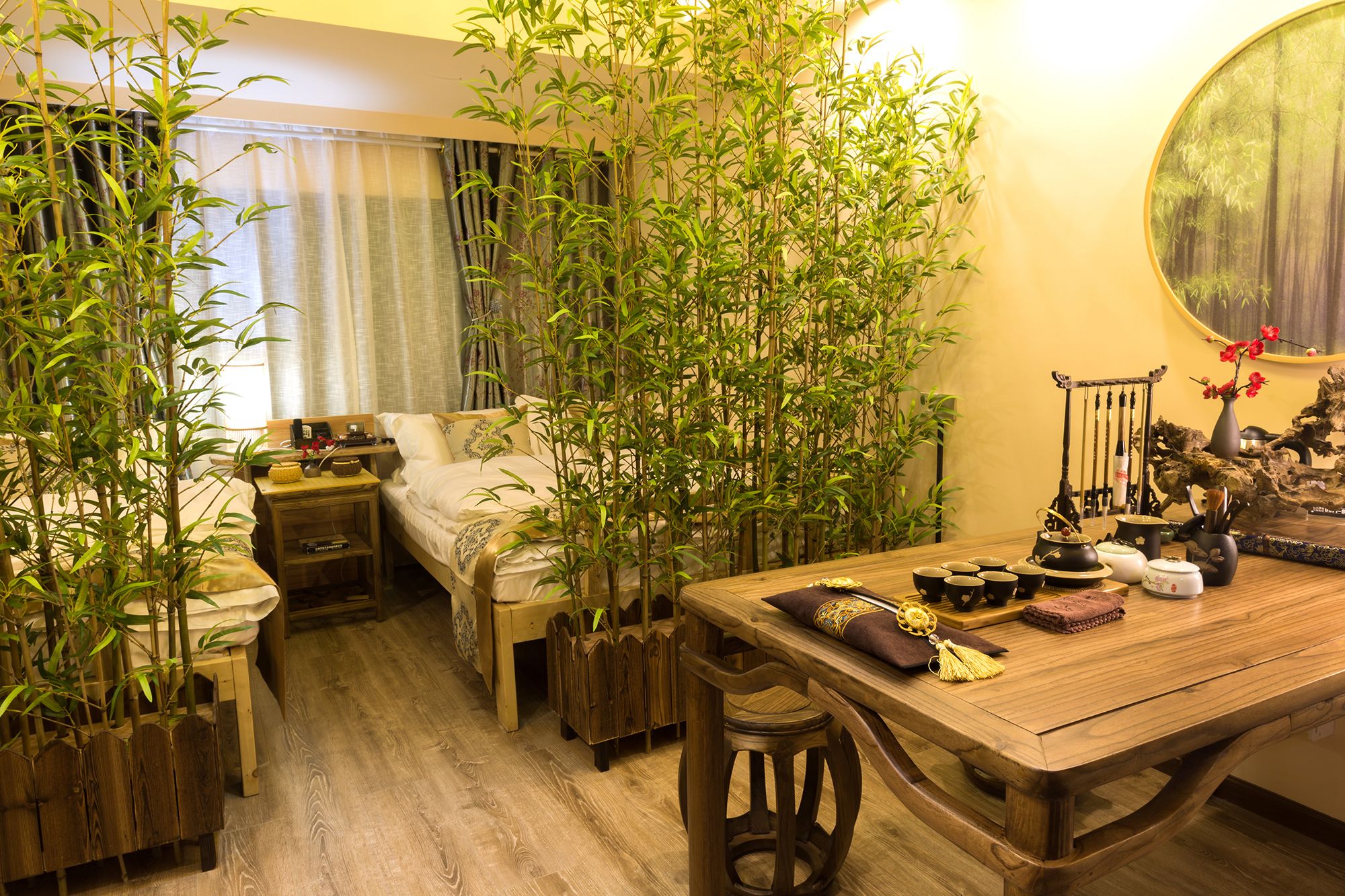 A traditional Japanese-style room with a bed, a wooden table with tea set, and bamboo plants.