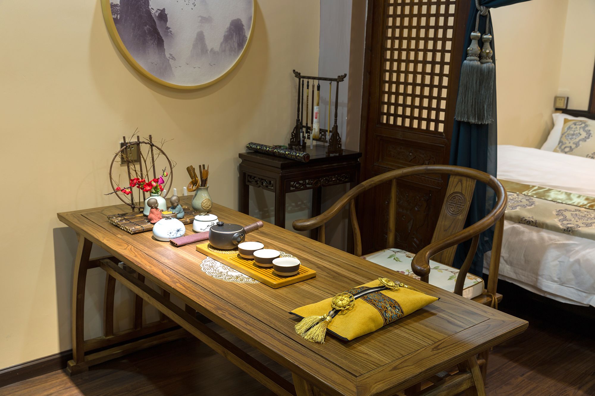 A traditional wooden dining table with teapots, cups, and a decorative pillow.