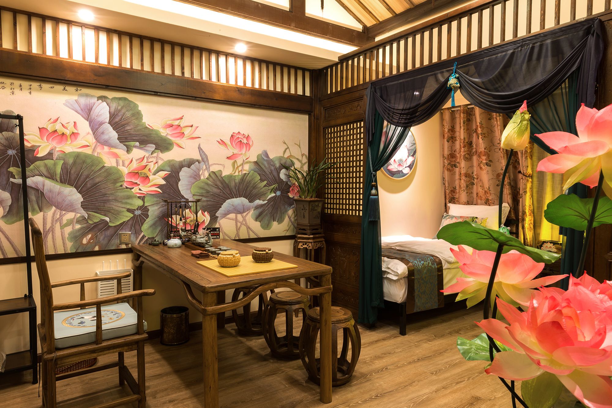 A traditional-style room with a wooden table, chairs, a bed, and a wall with a floral mural.