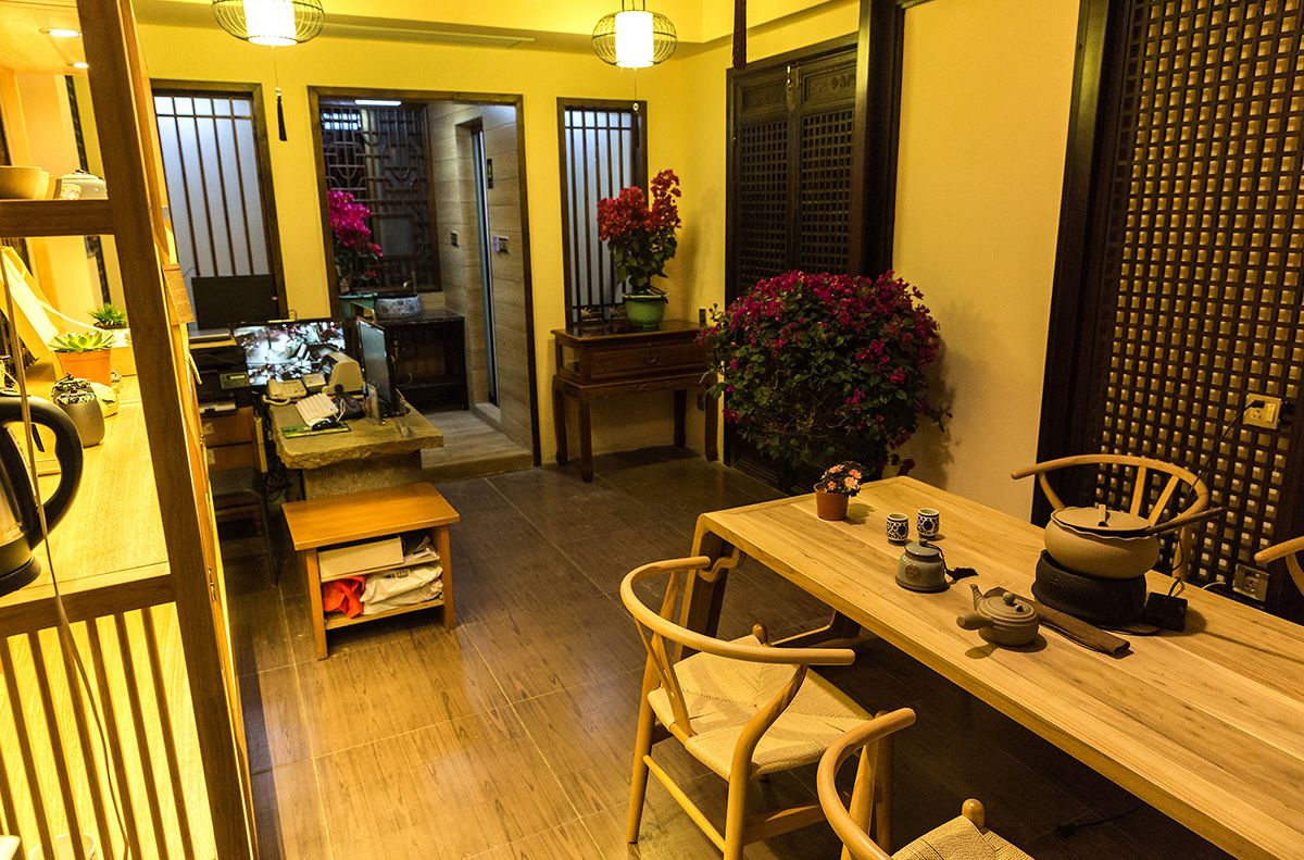 Una habitación tradicional japonesa con suelo de tatami, una mesa de madera baja con sillas, un televisor y una planta en maceta.