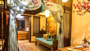 Une chambre traditionnelle avec un lit en bois, une petite table avec un service à thé et un grand tableau au mur.