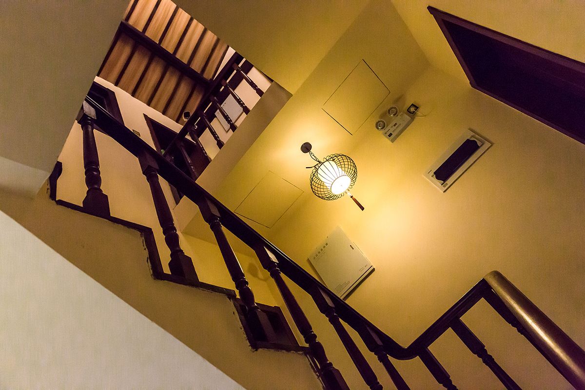 Una escalera con barandales de madera y una lámpara fijada a la pared.