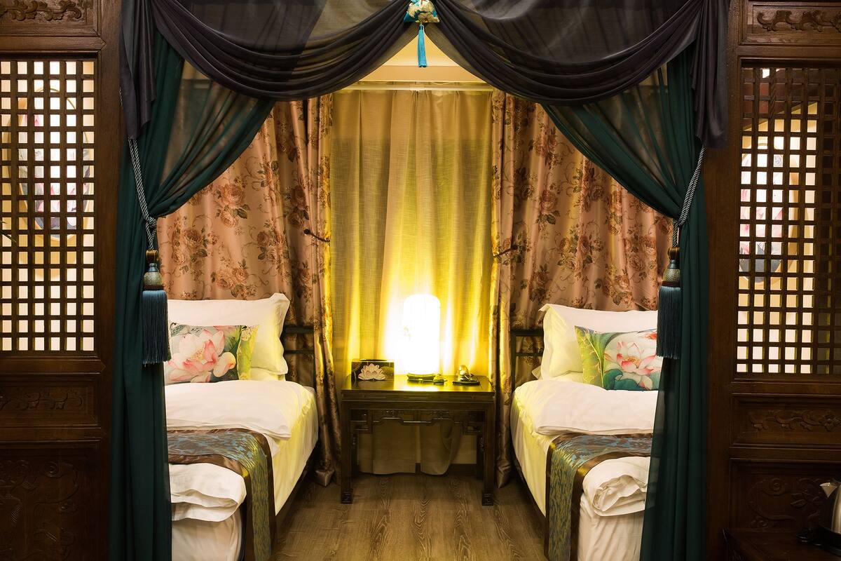 Una habitación con dos camas, una mesita de noche y una lámpara.