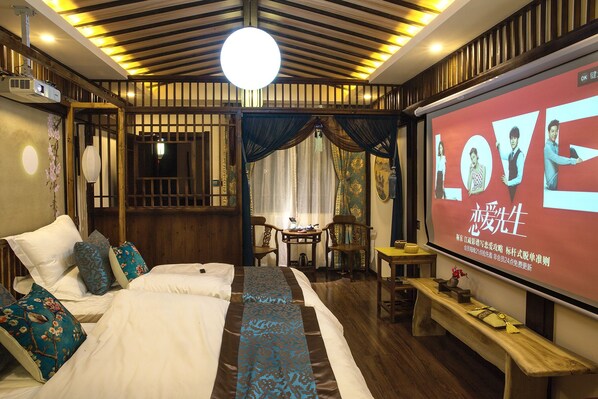 A traditional-style bedroom with a bed, pillows, a desk, and a screen displaying a movie. - FTYS Hostel (Hangzhou)