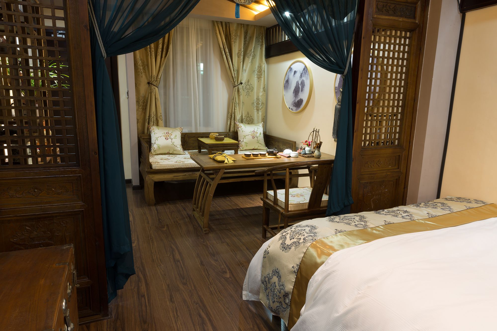 A traditional room with a bed, a wooden table with a tea set, and a sofa.