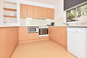 Una cocina moderna con armarios de madera, microondas, horno y lavavajillas.