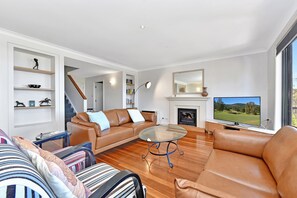 Una sala moderna con un sofá de cuero, una mesa de centro de vidrio, una chimenea y un televisor.