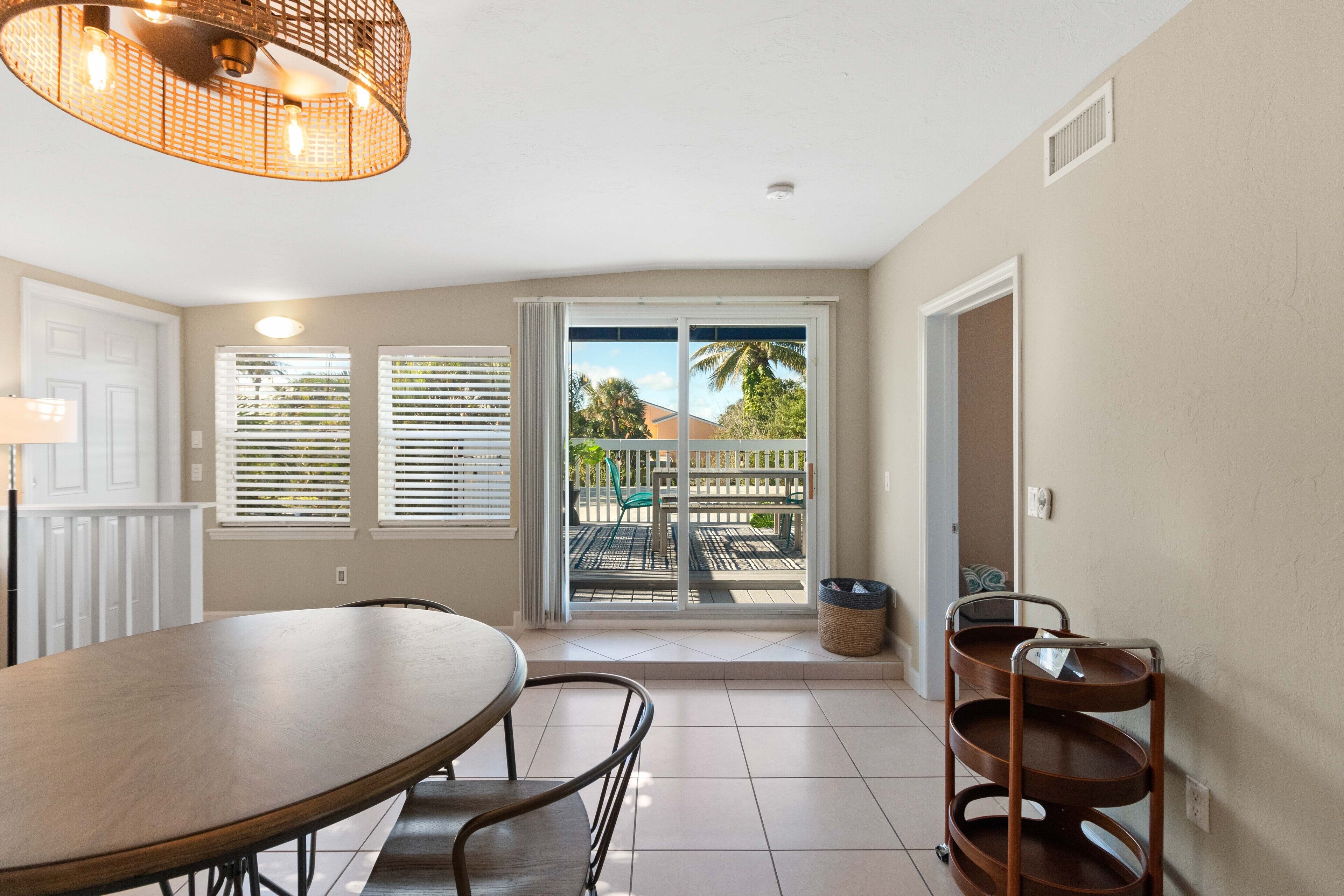 A dining area with a round table and chairs, a ceiling light fixture, and a sliding glass door leading to an outdoor patio.