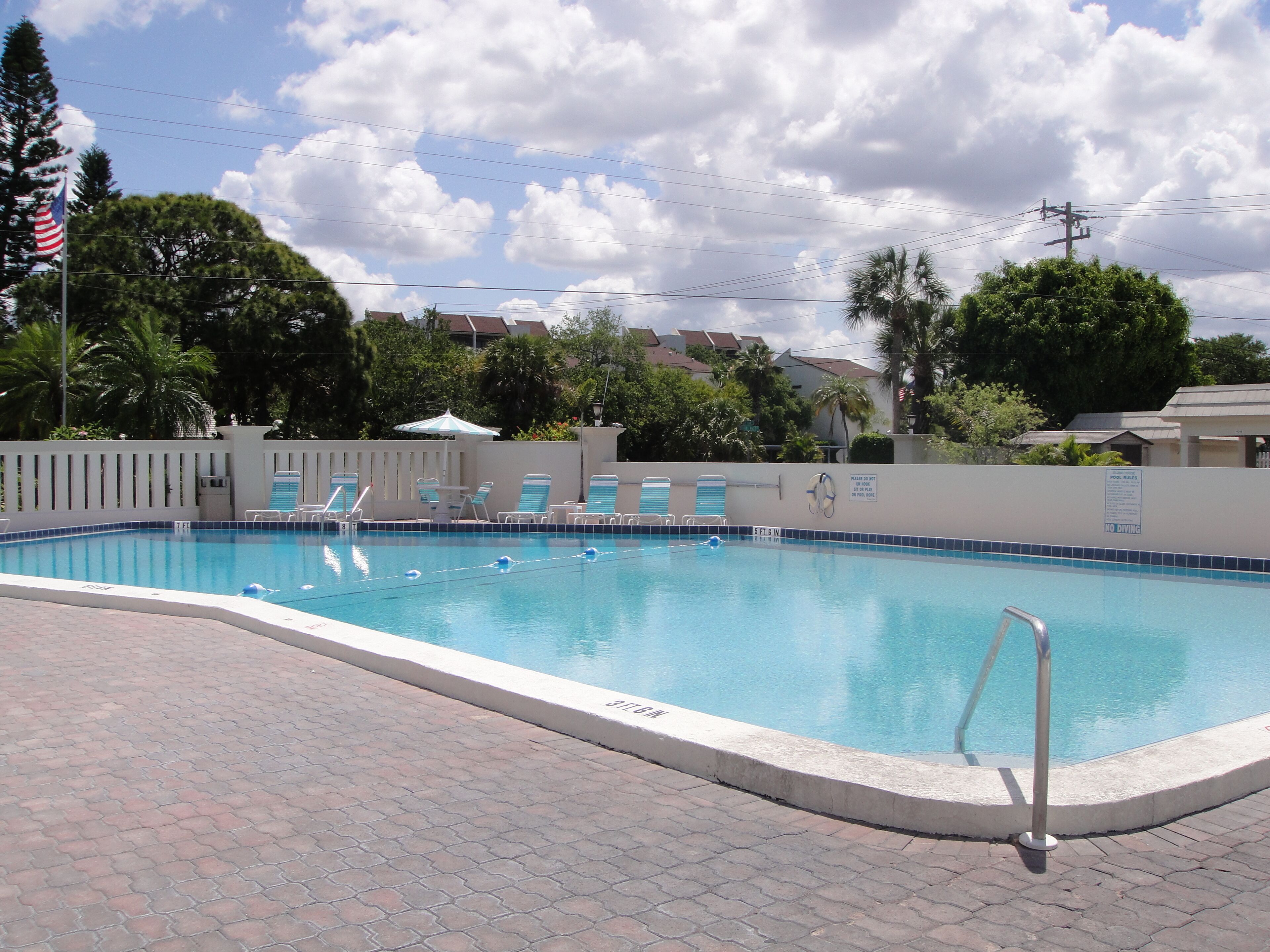 Une piscine équipée d’un poste de surveillance pour le sauveteur, de chaises longues et d’un panneau indiquant les règles à respecter.