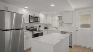 Una cocina moderna con armarios blancos, electrodomésticos de acero inoxidable y una isla central.