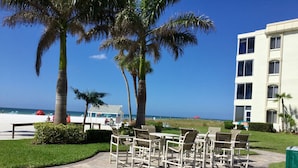 Un patio con mobiliario exterior, palmeras y vistas a la playa y al océano.