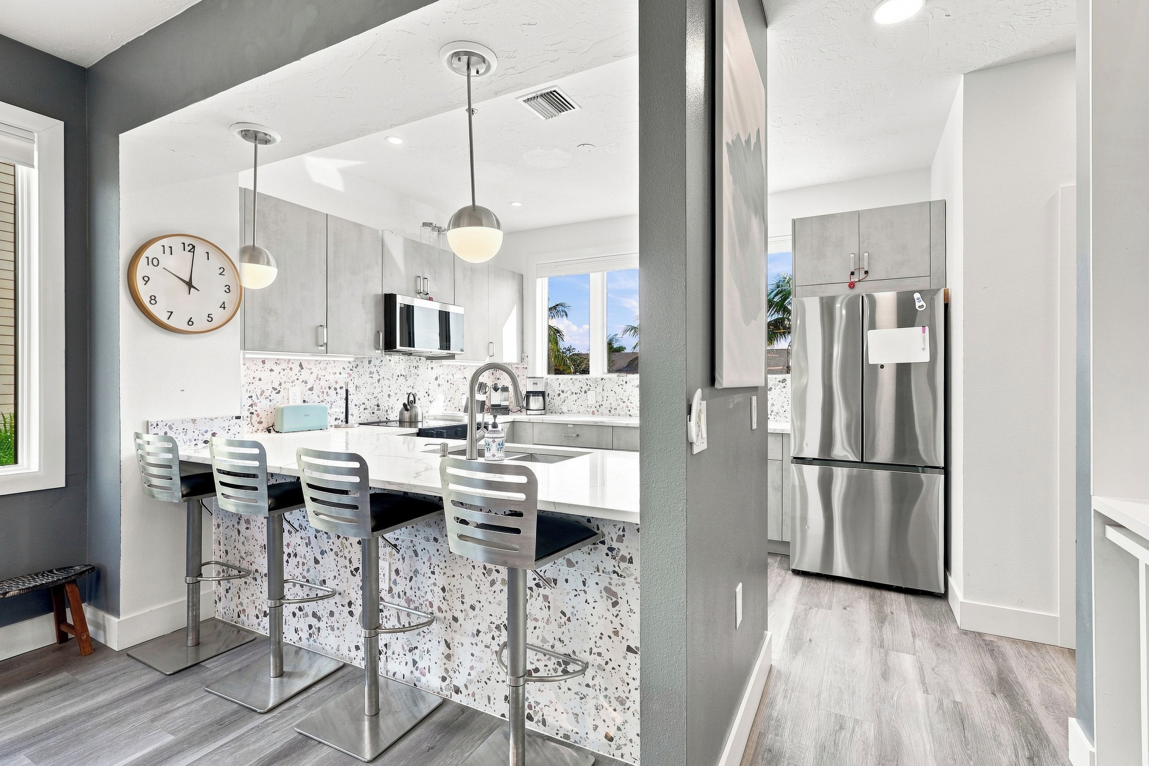 A modern kitchen with a central island, stainless steel appliances, and a large window.