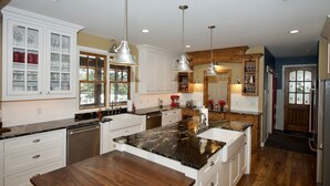 A modern kitchen with white cabinetry, a granite countertop, and pendant lighting.