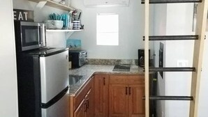A compact kitchen with a microwave, toaster, and wooden cabinets. - Studio Apt by beach - unit #14 (Scarborough)