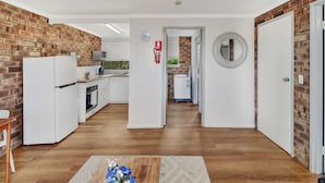 Una cocina moderna con electrodomésticos blancos, una pared de ladrillo y piso de madera.