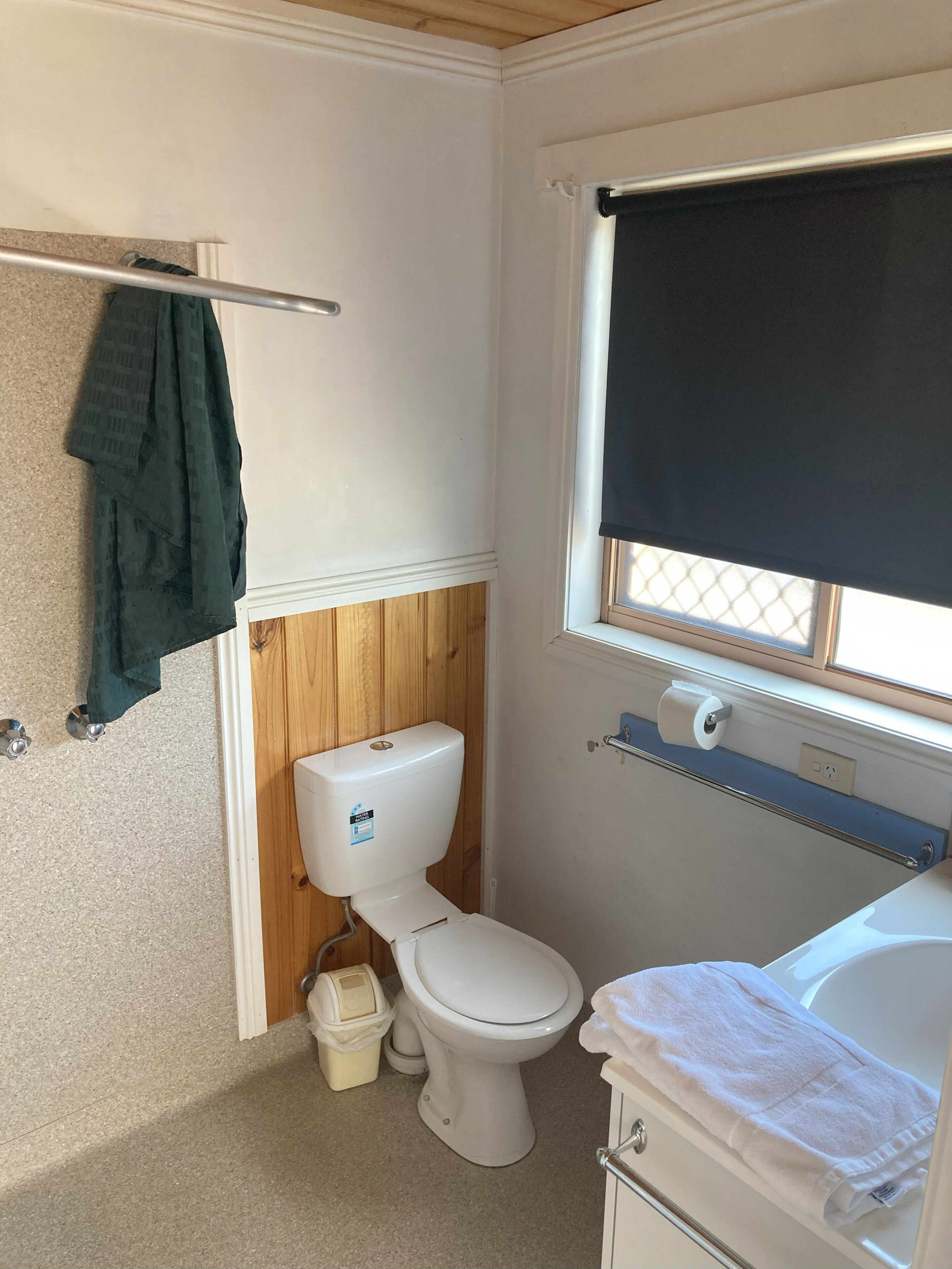 Un baño pequeño con inodoro, lavamanos y ventana con persiana.