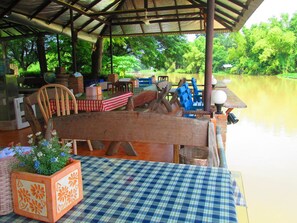 Un espacio al aire libre cubierto con mantel a cuadros, sillas de madera y un banco.