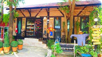 A rustic bar with a brick facade, wooden beams, and a welcoming sign.