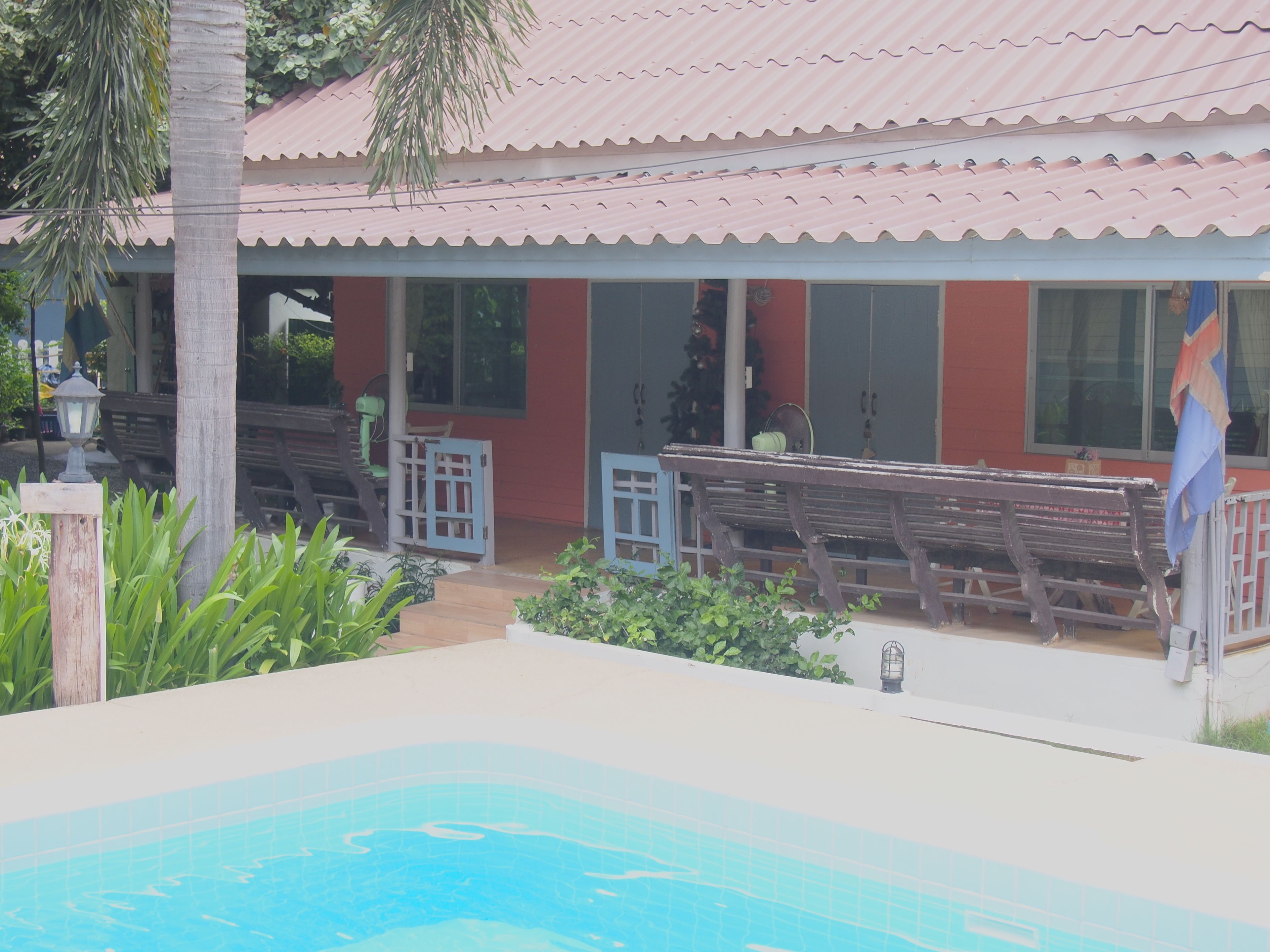 Un área de piscina con un deck de baldosas, bancos y una bandera.