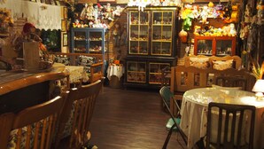 Een gezellige kamer met houten meubels, een eettafel en een kast vol diverse spullen.