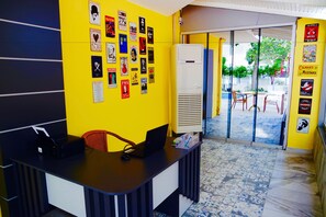 Un mostrador de recepción con una computadora portátil, una silla y una pared decorada con varios carteles.