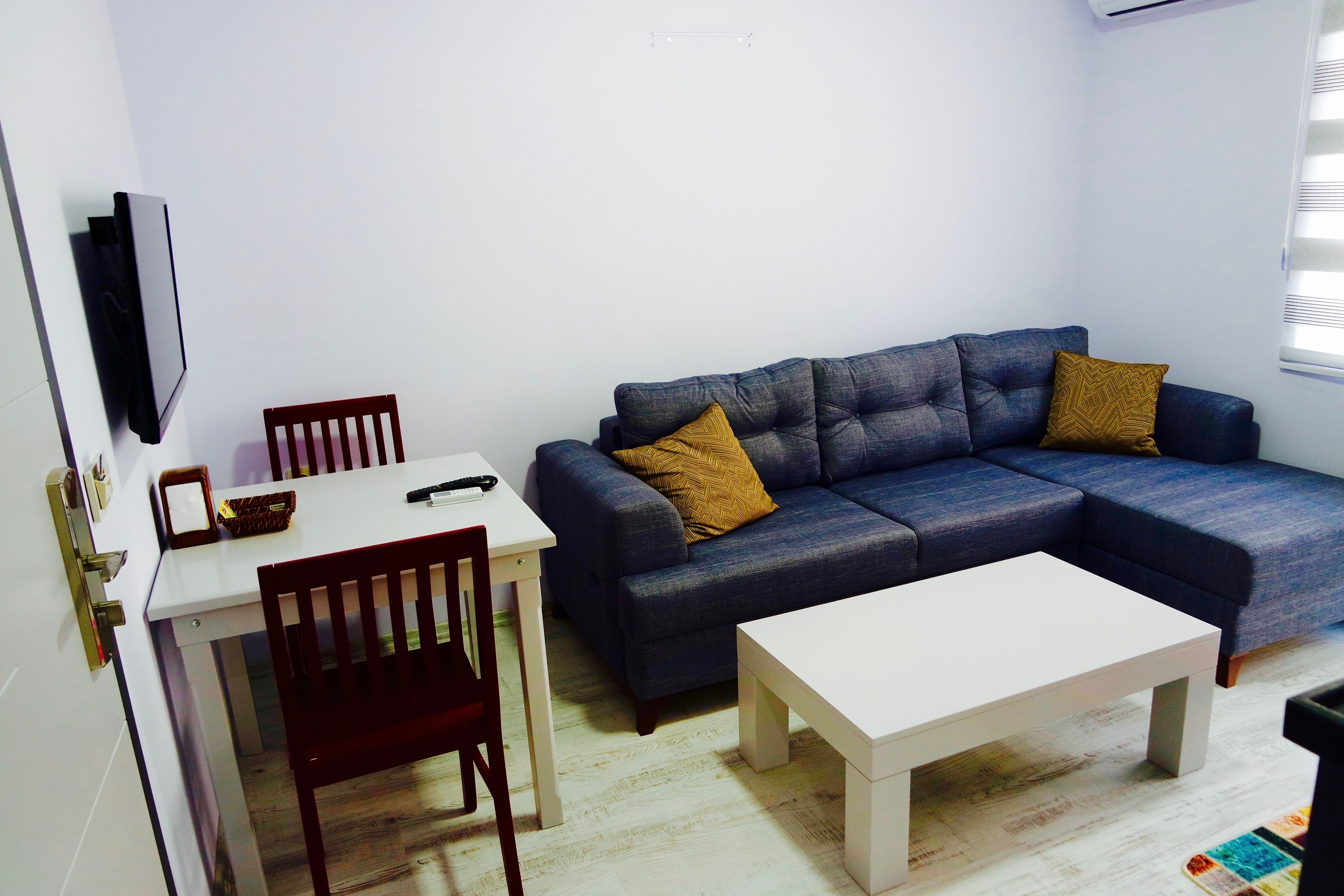 A living room with a dark blue sofa, a white coffee table, and a wooden dining table with chairs.