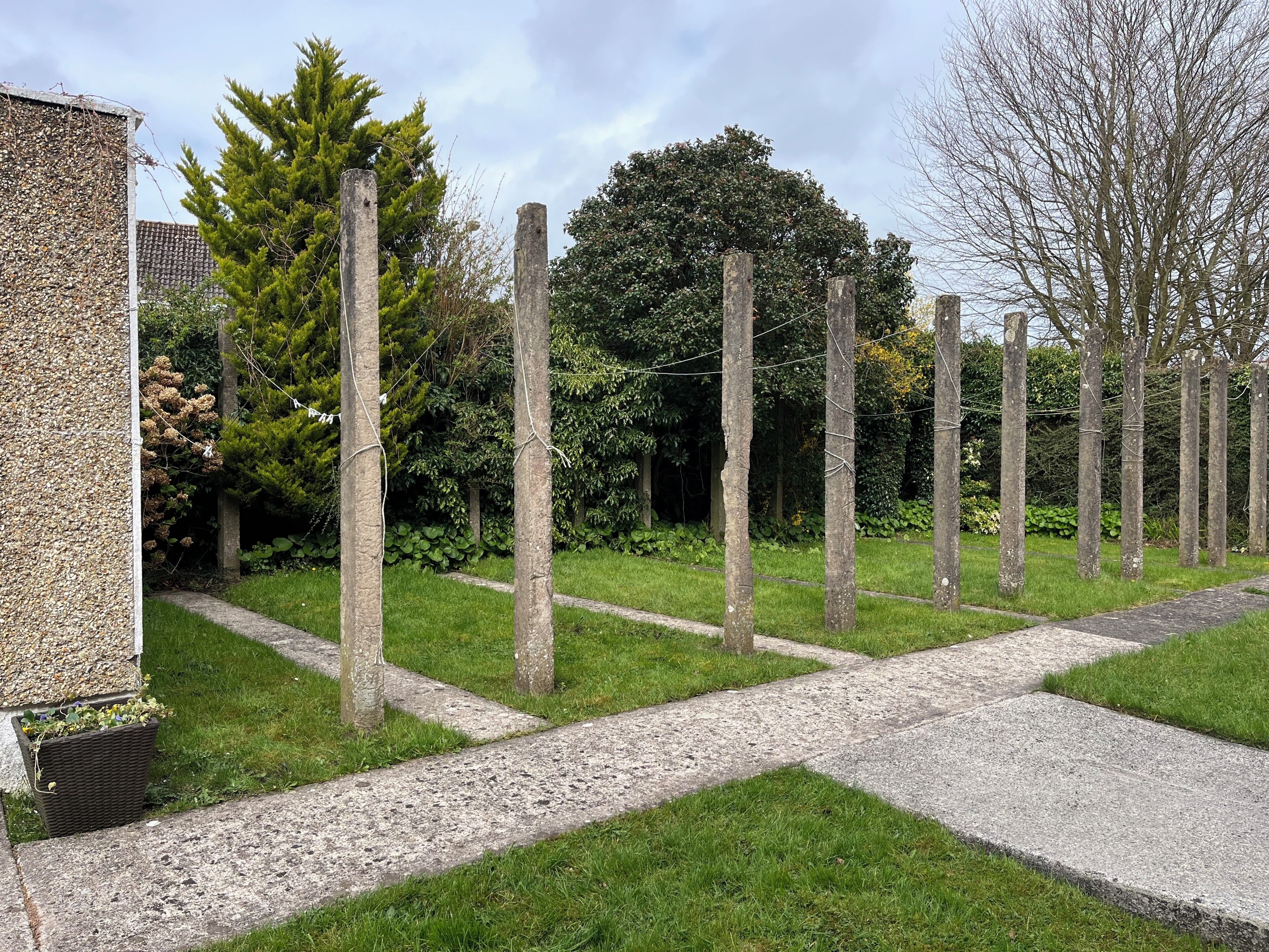 Um jardim com trilho de cascalho, árvores e um edifício com parede texturizada.