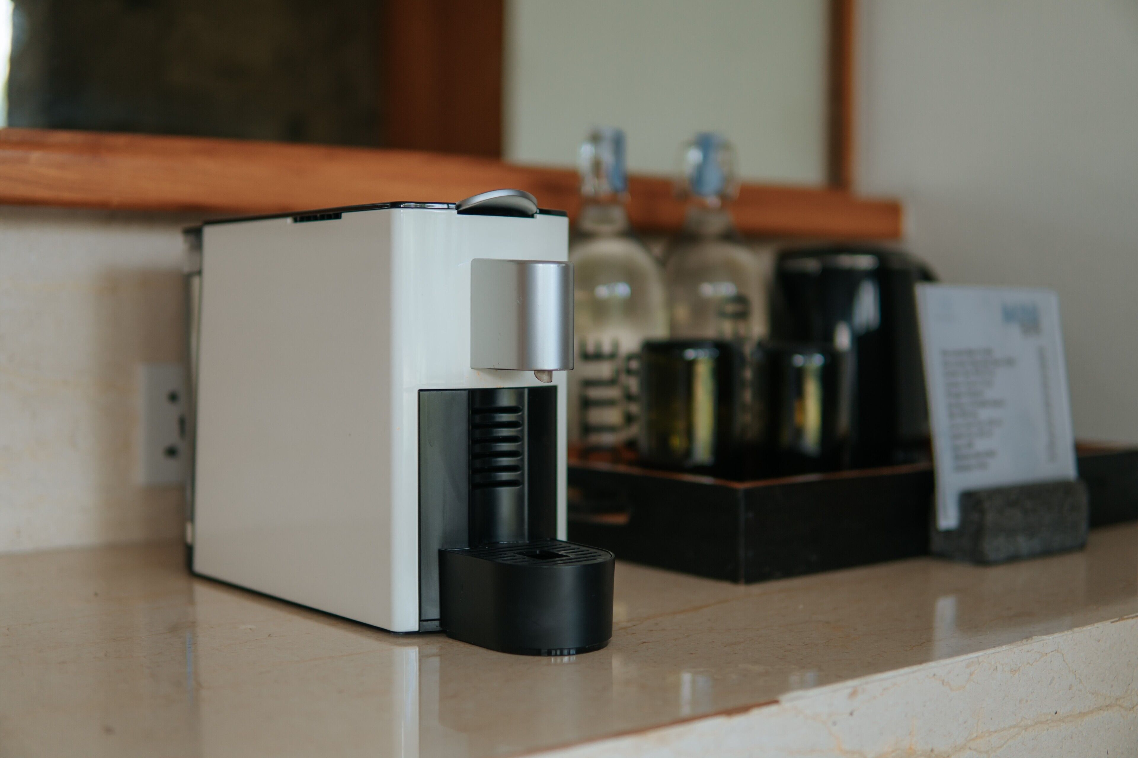 A coffee machine on a countertop with a wooden shelf in the background.