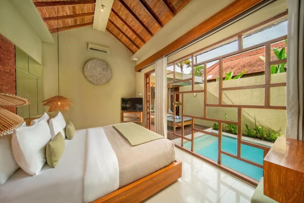 A bedroom with a bed, a TV, and a view of a swimming pool.