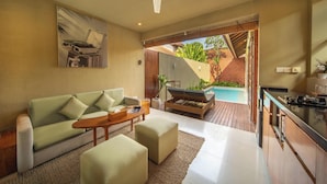 A modern living room with a sofa, ottoman, and coffee table, a ceiling fan, and a view of an outdoor pool area. - Manca Villa Canggu by Ini Vie Hospitality (Canggu)