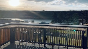 A deck with chairs overlooking a lake and forest. - House on the hill with Spectacular Port Bay Views (Port Campbell)