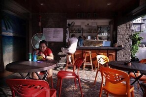 A restaurant interior with round tables, red and orange chairs, a bar area, and a menu board. - Stay Malate (Wanderers Guest House) (MANILA)