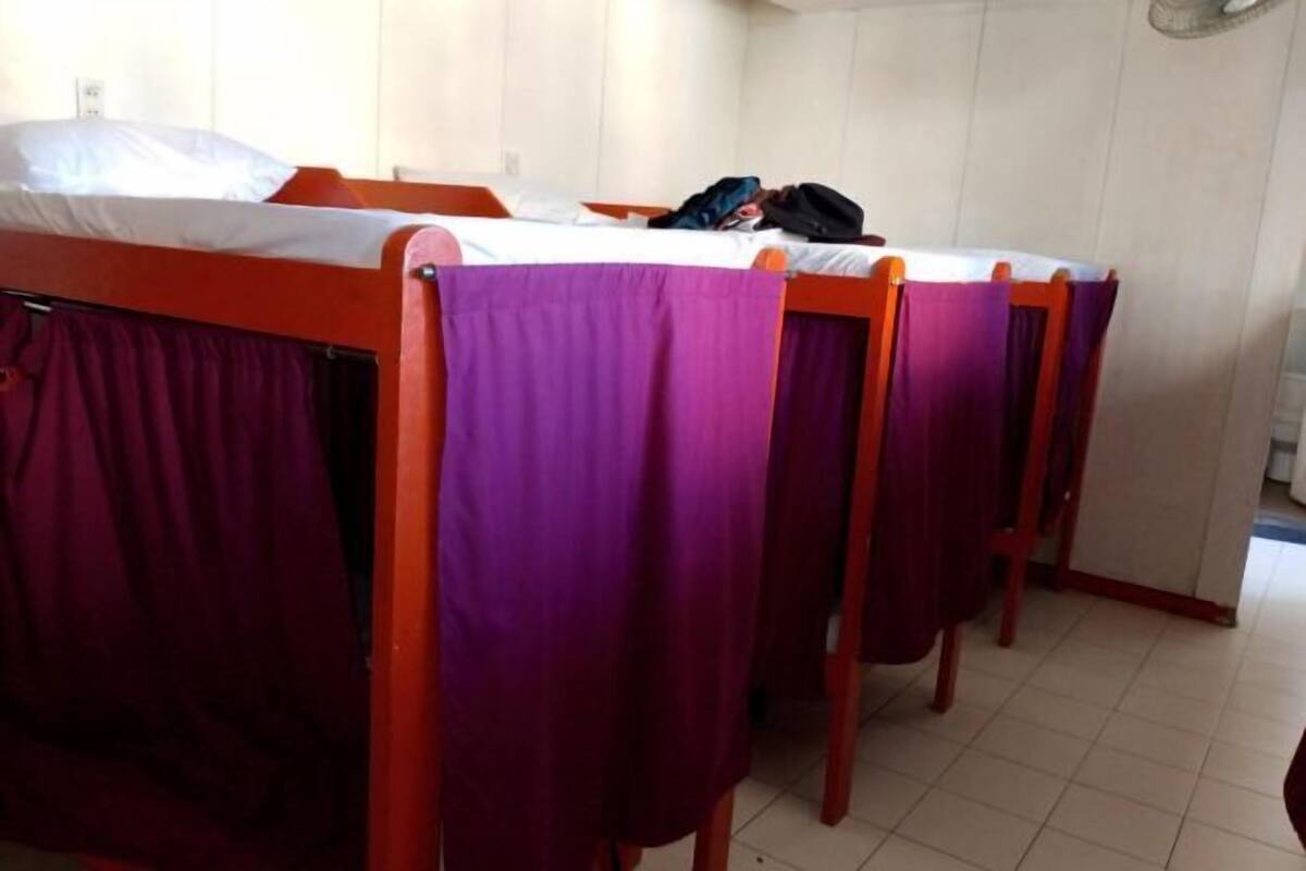 A room with three wooden bunk beds, each with a purple bedspread.