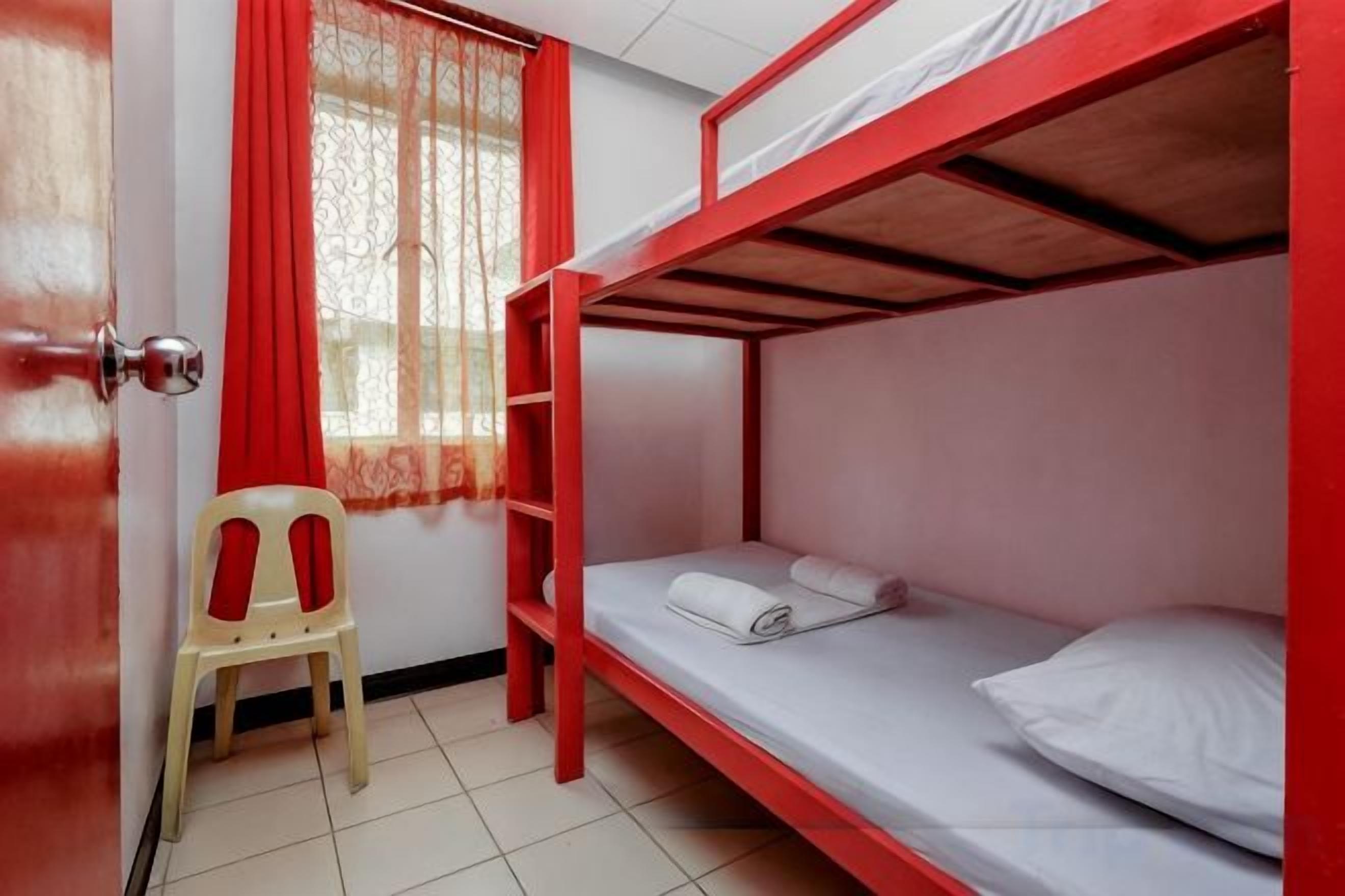 Habitación con literas, una puerta, una silla y una ventana con cortinas.