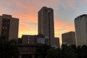 Eine Skyline mit hohen Gebäuden und einem Sonnenuntergangshimmel.