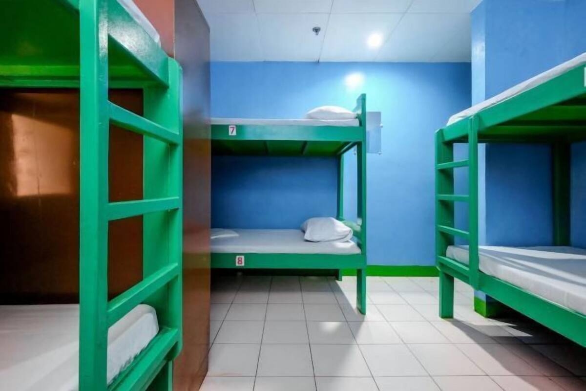 A dormitory room with bunk beds, a tiled floor, and a blue wall.