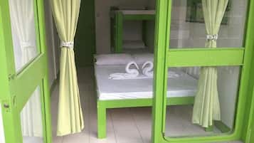 A room with bunk beds, a curtain tied at the top, and a white towel on the bed.