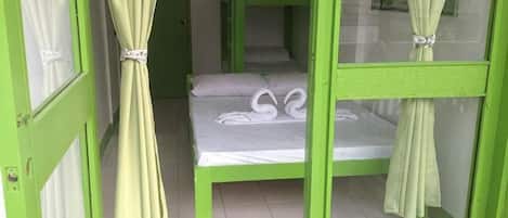 A room with bunk beds, a curtain tied at the top, and a white towel on the bed.