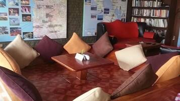 A seating area with a wooden table, cushioned sofas, and a bookshelf.
