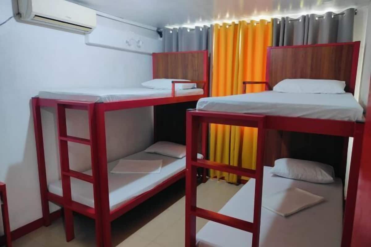 A room with bunk beds, a window with curtains, and an air conditioning unit.