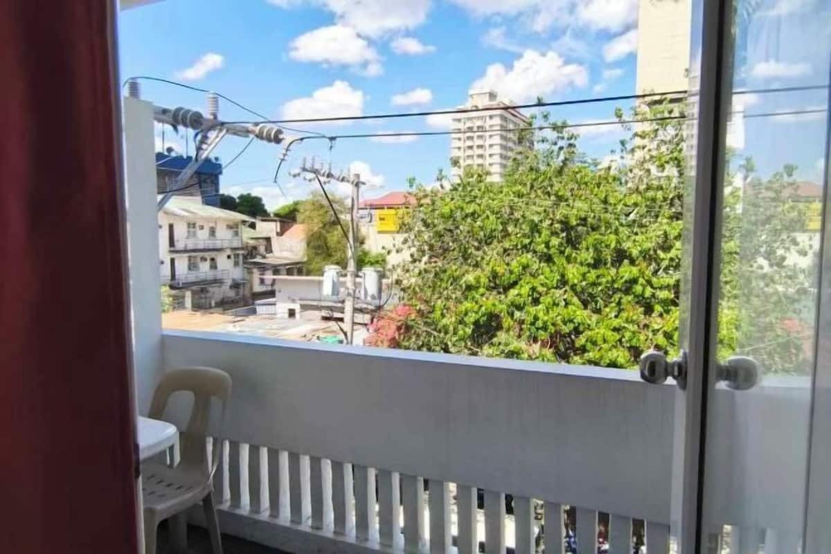 A balcony with a view of buildings and a tree.