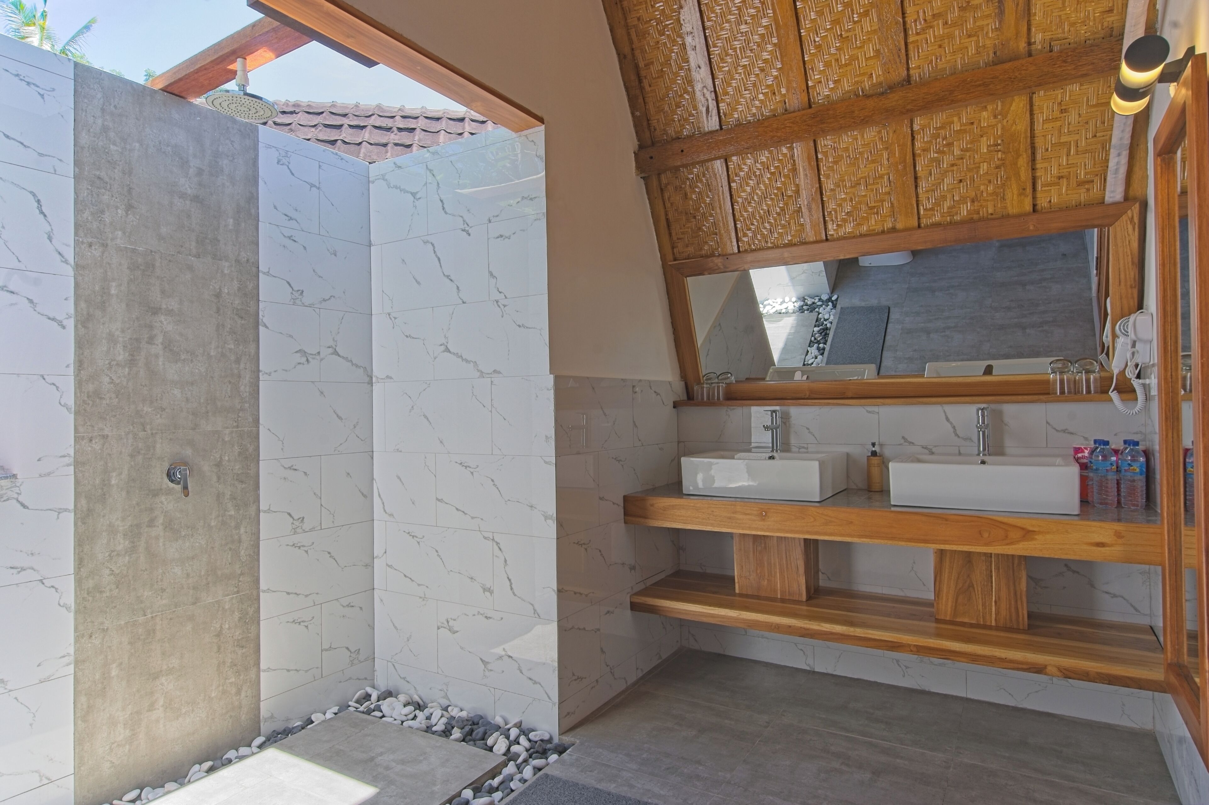 Een moderne badkamer met een douchecabine van beton, marmeren tegels, houten planken en een grote spiegel.